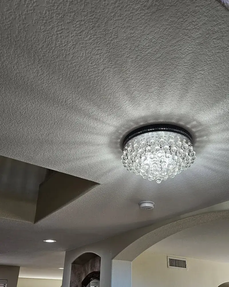 Crystal flush-mount light fixture glowing on a textured ceiling