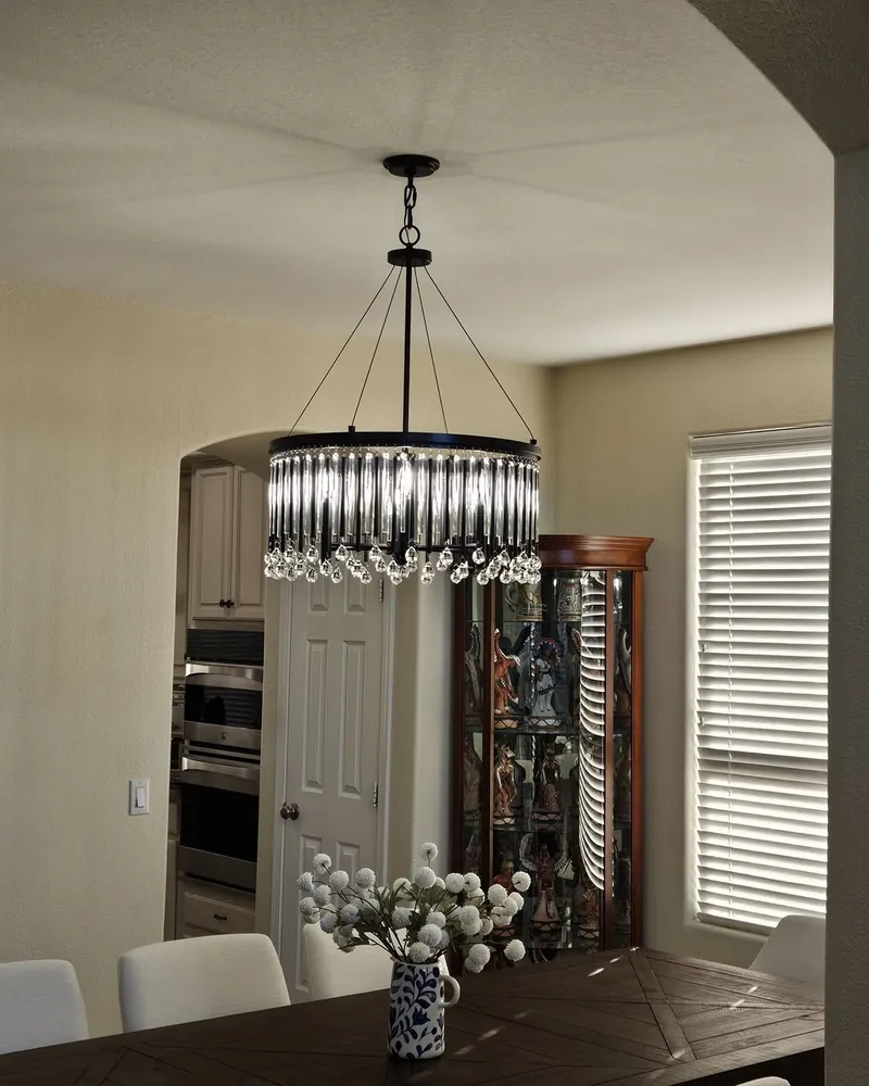 Crystal drum chandelier hung over a dining table beneath an arched doorway