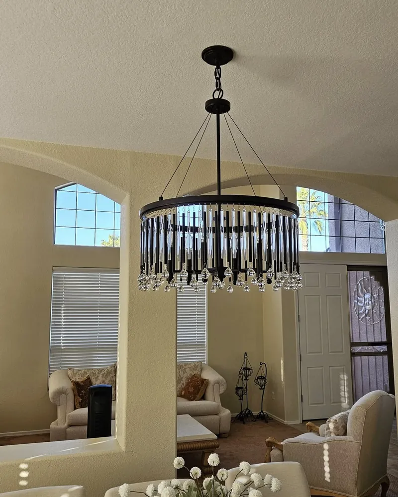 Drum crystal chandelier installed in a two-story living room with arched windows