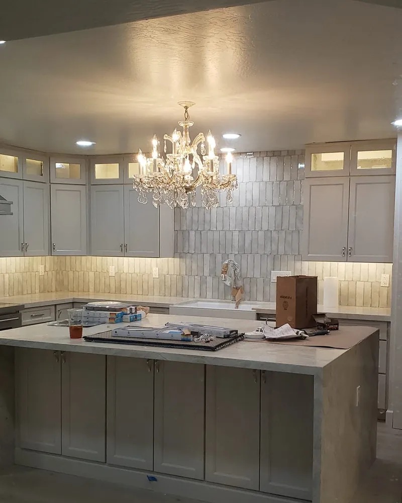 Remodeled kitchen with recessed lights, lit upper cabinets and a crystal chandelier over the island